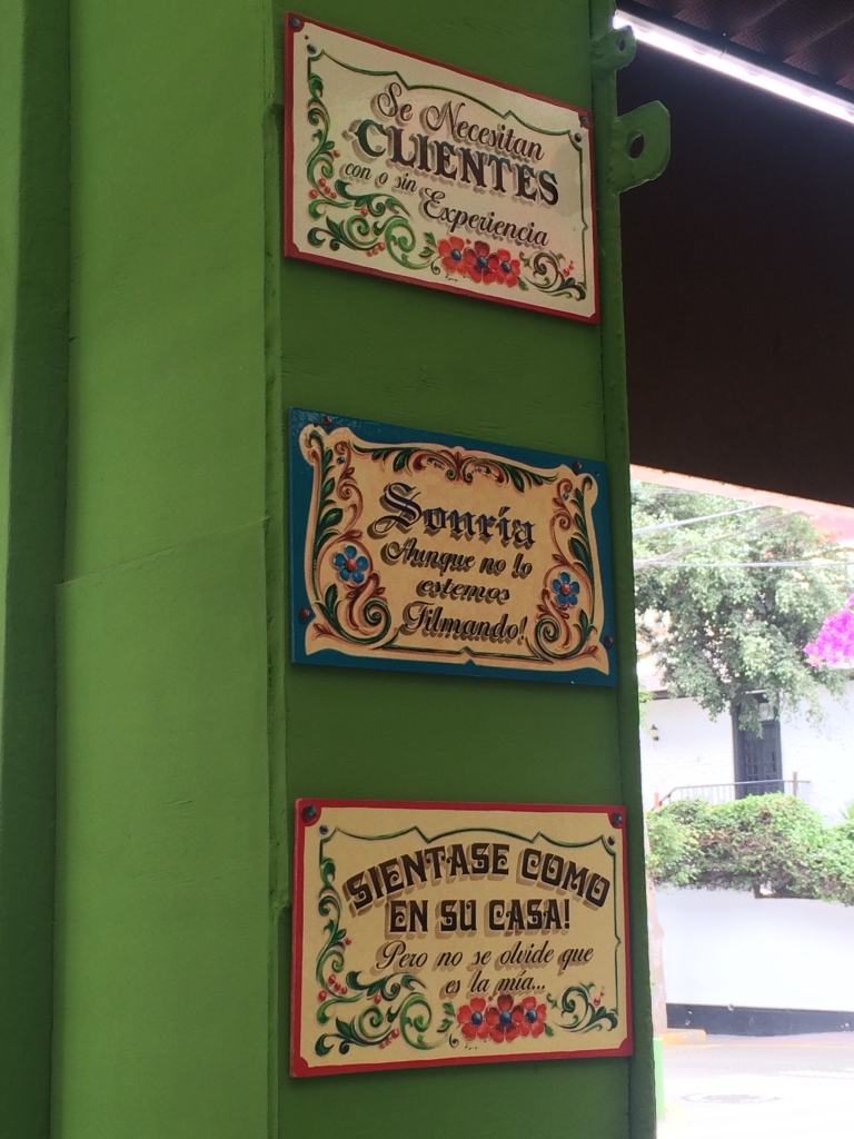 Signs at a vegetarian restaurant in Miraflores, Lima. "Clients needed with or without experience" "Smile, although we are not filming it" "Sit as if you are at home, but don't forget that it is mine"